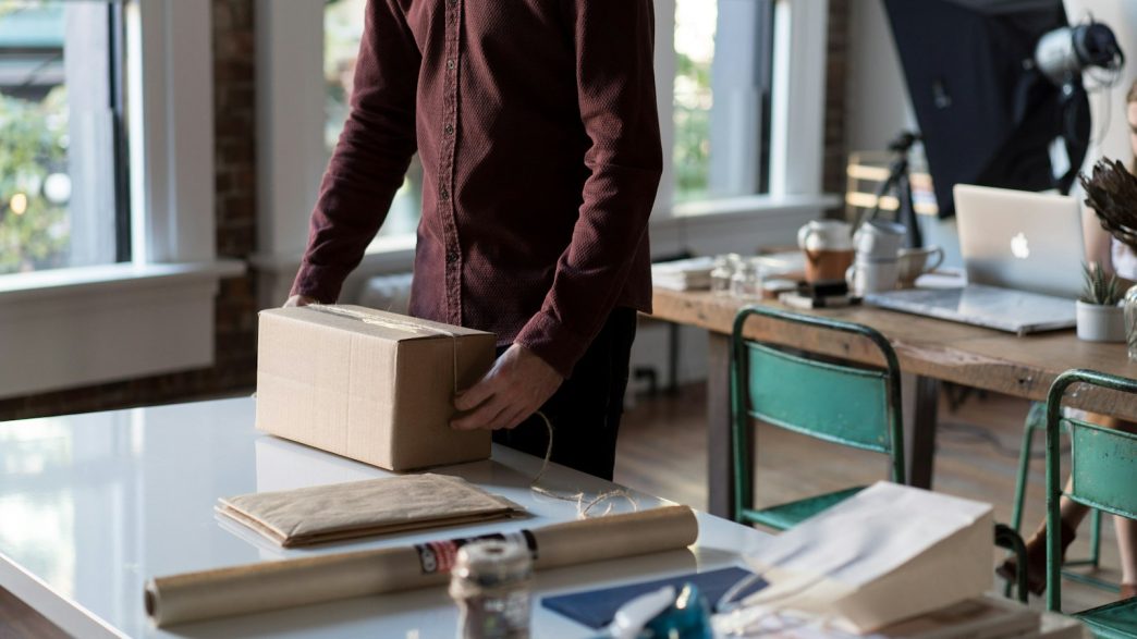 person holding cardboard box on table